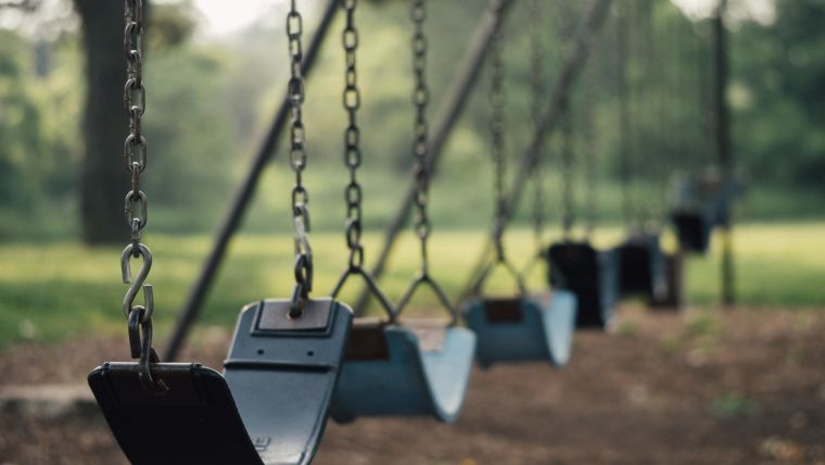 An empty row of swings in a play park.