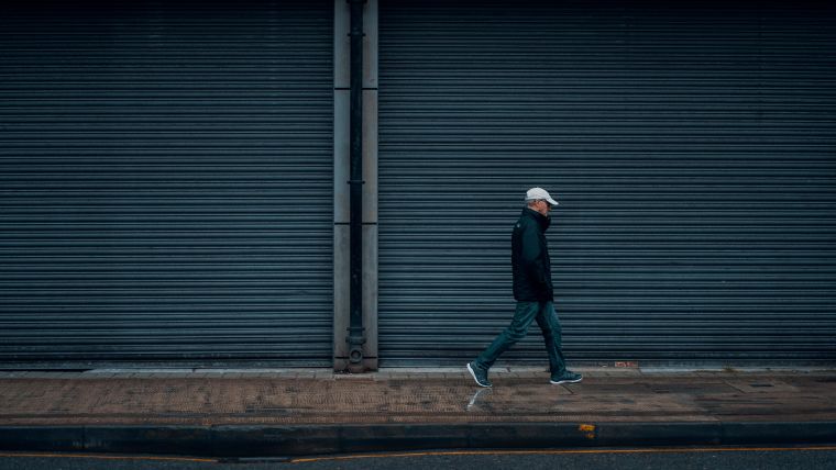 Man walking on empty city street with closed shops